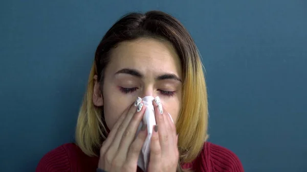 Uma jovem pulveriza um remédio frio no nariz. A rapariga assoa o nariz num guardanapo de papel. Close-up — Fotografia de Stock