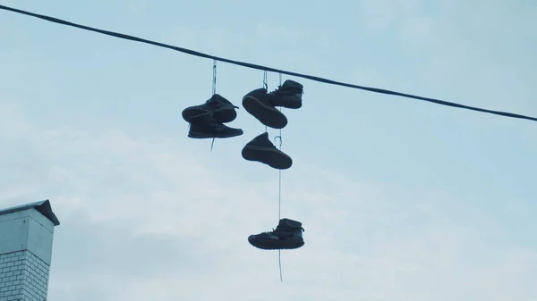 Şehrin caddesinde dokuz metre yüksekliğinde elektrik kablolarında asılı üç çift spor ayakkabı.