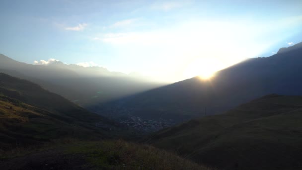 Puesta de sol en las montañas caucásicas time-lapse. El sol se pone detrás de altas montañas cubiertas de nubes y niebla. — Vídeo de stock