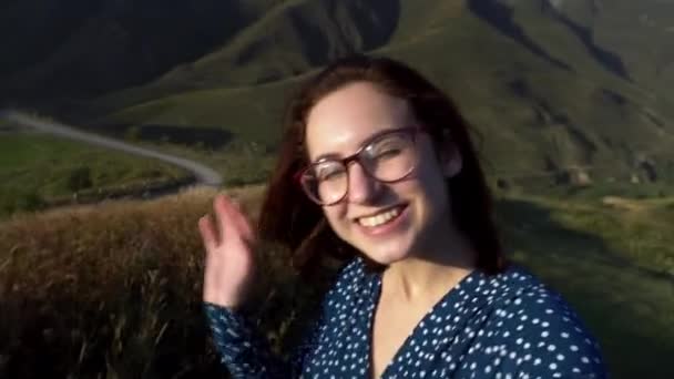 Jovem mulher de óculos e vestido atira vídeo blog nas montanhas caucasianas. — Vídeo de Stock