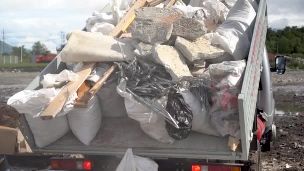 Un camion à benne décharge les déchets de construction. La machine soulève le corps et laisse tomber les sacs poubelles. — Video