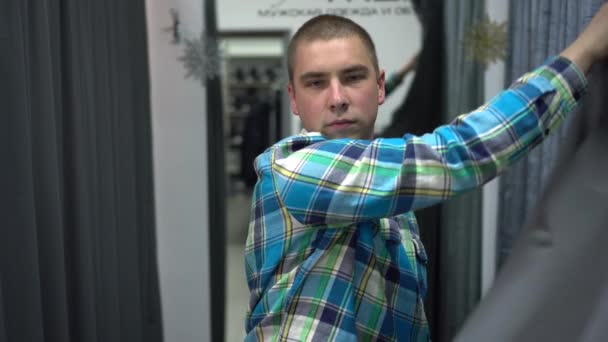 젊은 남자가 적절 한 방의 커튼을 엽니다. 의복 점. — 비디오