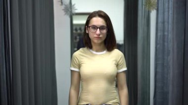 Genç kadın soyunma odasındaki perdeyi kapatıyor. Giysi mağazası.