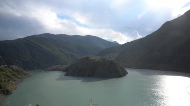 Dağların arasındaki göldeki yeşil adanın manzarası.