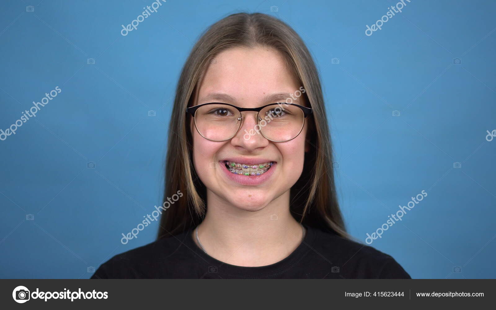Teen girl with braces smiling on a blue background. Girl with colored