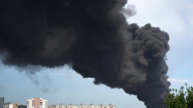 Binaların üzerinden siyah duman yükseliyor. Fabrika binasında büyük bir kimyasal yangın. Yoğun siyah duman gökyüzünü kaplıyor..
