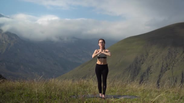 Mladá žena v teplákové soupravě se zabývá jóga představení trikonasana póza v horách. — Stock video