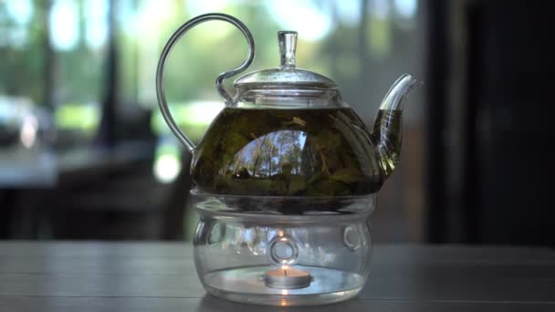 Glass teapot heated filled with green leaf tea in the restaurant. — Stock Video