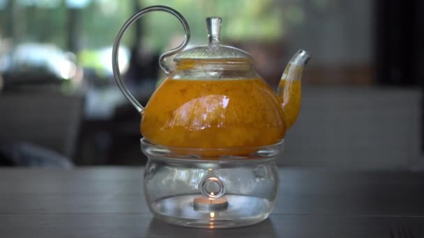Heated glass teapot filled with sea buckthorn tea in the restaurant. — Stock Video