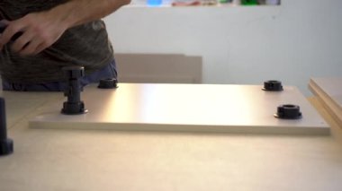 Mobilya üretim tesisinde bir adam tahta parçalarına fiş takıyor..