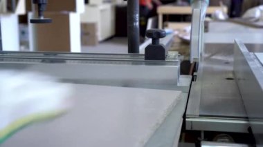Bir adam mobilya üretim tesisinde tahta parçaları dairesel testere ile kesiyor..