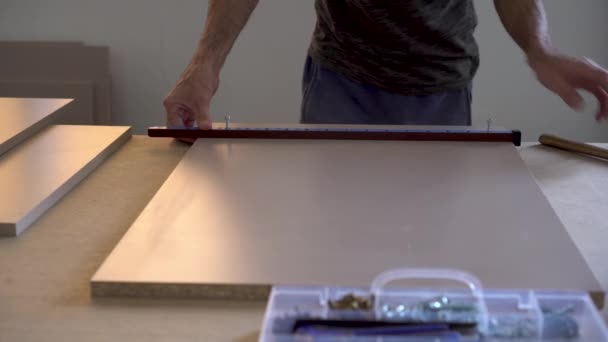 Ein Mann macht in einer Möbelfabrik Markierungen an Holzteilen. — Stockvideo