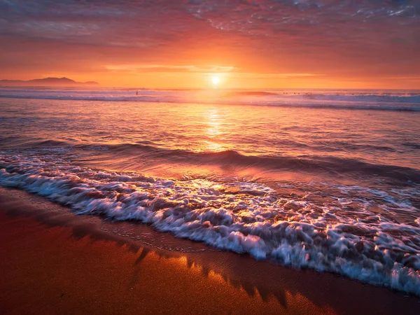 Schöner roter Sonnenuntergang am Strand mit einer Welle am Ufer — Stockfoto