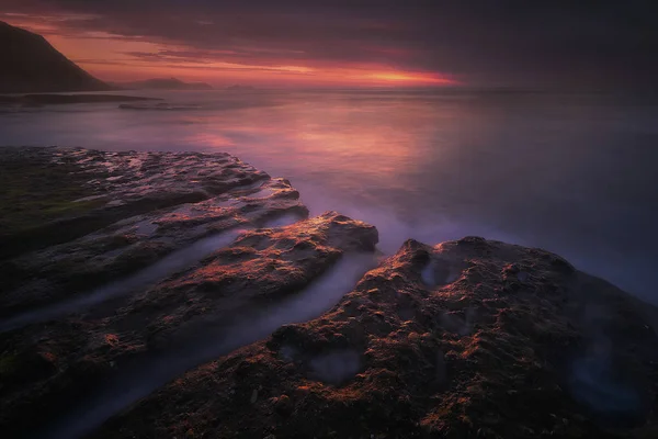 Темный морской пейзаж на побережье со скалами в сумерках — стоковое фото