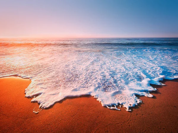 Belo pôr do sol na praia com uma onda na costa — Fotografia de Stock