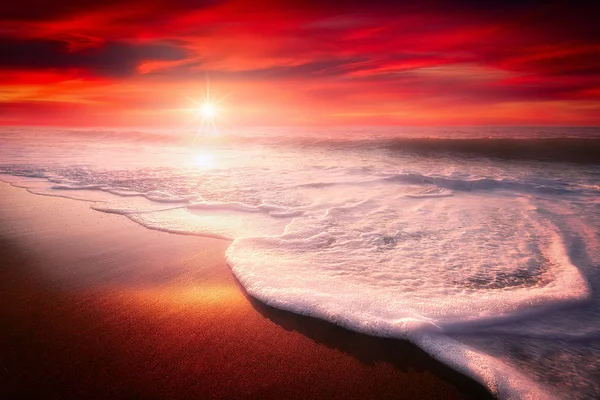 Красный закат на пляже с волной на берегу — стоковое фото