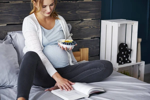 Беременная Женщина Ест Читает Книгу — стоковое фото