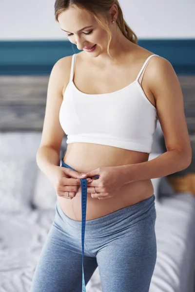 愉快的孕妇测量她的腹部在卧室 — 图库照片