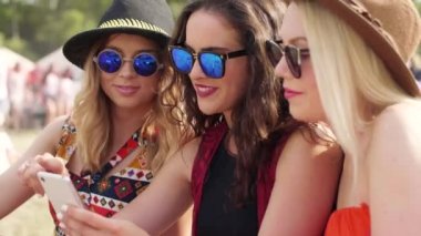 Çimenlerin üzerinde oturan ve bir cep telefonu kullanarak arkadaşlar