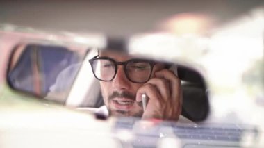 Bir arabada akıllı telefonla konuşan adam
