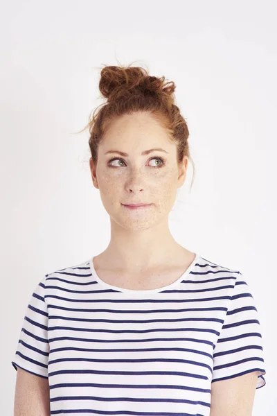 Thoughtful woman biting her lips at studio shot