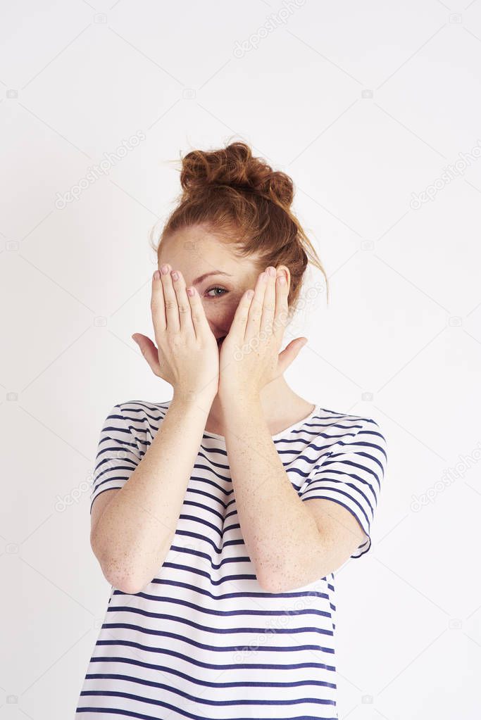 Portrait of shy woman covering face with hands at studio shot