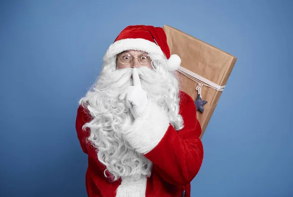 Santa claus holding christmas presents behind his back
