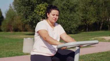 Egzersiz bisikleti genel parkta kullanan yorgun kadın