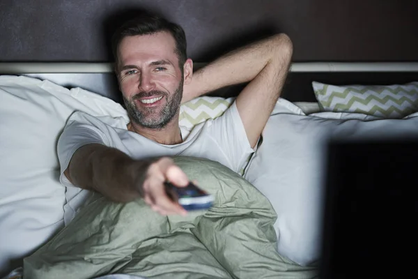 ベッドに横になっていると 夜にテレビを見ている男 — ストック写真
