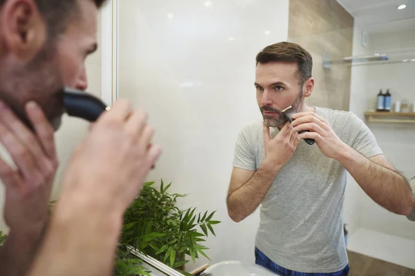 在浴室里用电动剃须刀剃须的成熟男子 — 图库照片