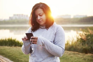Kadın atlet genel Park'ta bir cep telefonu kullanarak