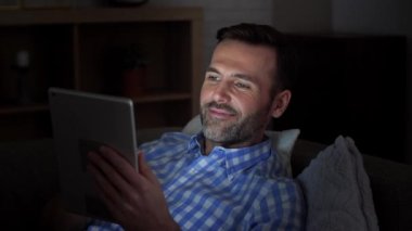 Adam kanepede yatan ve geceleri tablet kullanma