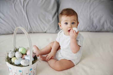 Oynak bebek yatakta Paskalya yortusu yumurta yeme