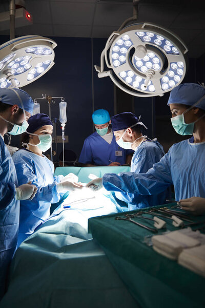 Team of surgeons during serious operation in darkness  