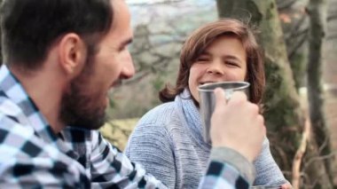 Bahar yürüyüşü sırasında çay içen neşeli adam ve genç çocuk