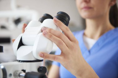 Diş mikroskobu tutan diş hekiminin ellerinin kapatılması