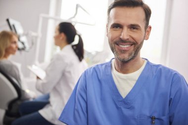 Diş hekimi kliniğinde gülümseyen erkek diş hekimiön görünümü