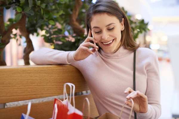 大きな買い物の後に携帯電話で話す若い女性 — ストック写真