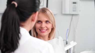 Diş hekimi kliniğinde gülümseyen kadın ve diş hekimi arasındaki konuşma