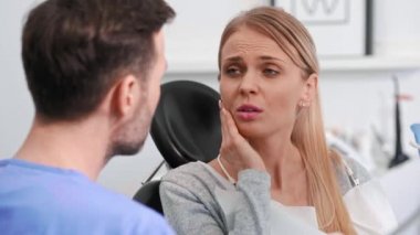 Diş ağrısı çeken genç bir kadın dişçi kliniğinde dişçiyle konuşuyor.