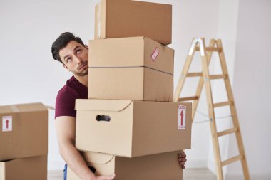 Ağır karton kutu yığını taşıyan adam 