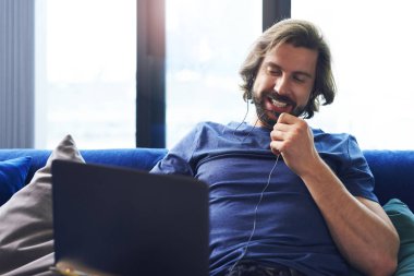 Oturma odasında dizüstü bilgisayar kullanan genç yetişkin adam