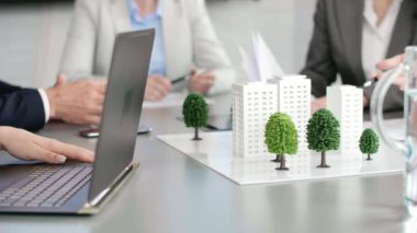 Tabloda mimari model ve arka planda mimarlar