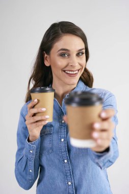 Tek kullanımlık bir fincan kahve tutan gülümseyen kadının portresi