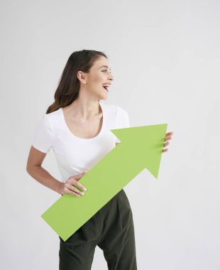 Excited woman holding rising arrow in studio shot clipart