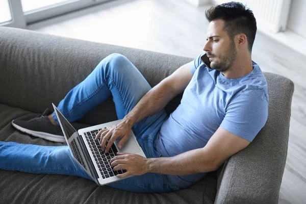 Junger Mann Mit Handy Und Laptop Wohnzimmer — Stockfoto