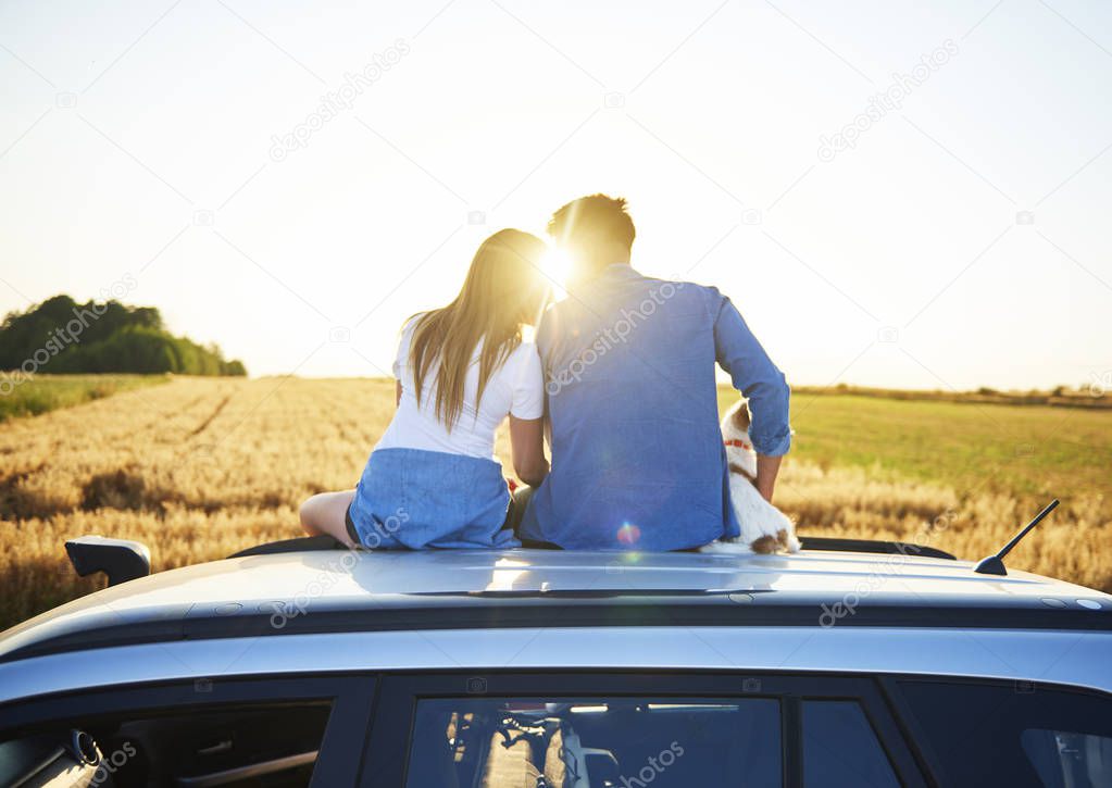 Rear view of loving couple embracing and sitting on car 