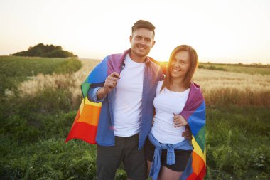 Portrait of smiling young couple with  rainbow flag  clipart