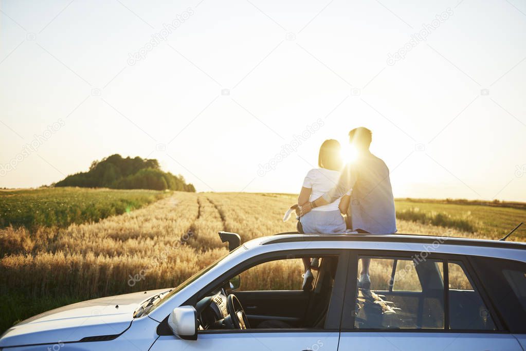 Rear view of affectionate couple catching a break during road trip 