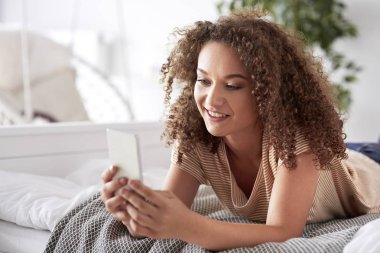Yatakta akıllı telefon kullanan güzel kadın 